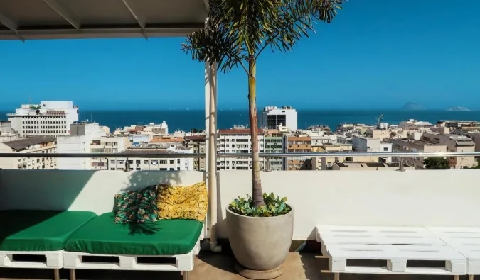 Sunny rooftop terrace with green pallet furniture and panoramic ocean and city views.