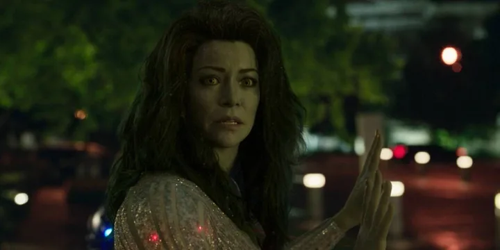 She-Hulk character with green skin stands outdoors at night in a sparkly outfit, looking alarmed.