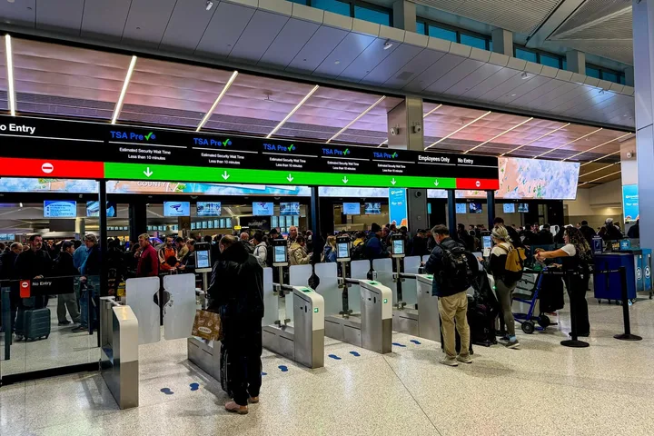 Passengers passing through TSA PreCheck security lanes at a busy airport checkpoint.