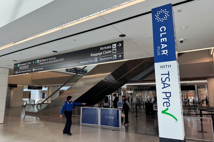 CLEAR Plus with TSA PreCheck checkpoint area at SFO airport with a staff member directing travelers.