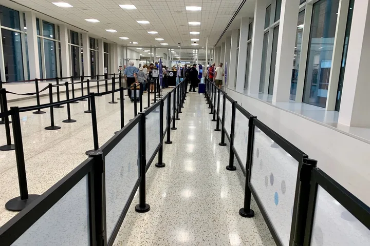 Empty airport security queue with stanchion barriers stretching toward a distant checkpoint.