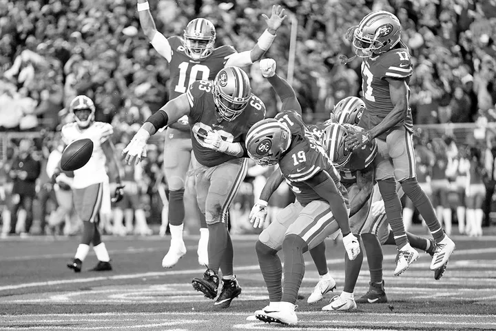 San Francisco 49ers players celebrating a touchdown on the field during an NFL game, black and white.