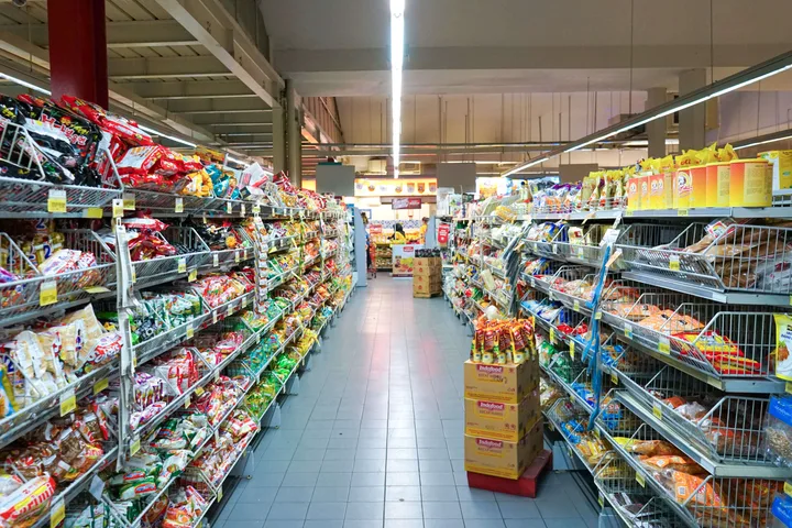 Wide supermarket aisle lined with colorful packaged snack products on both sides.