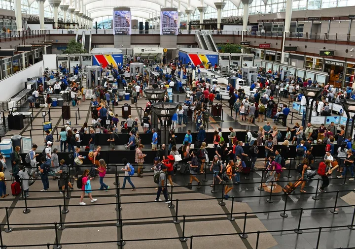 Overhead view of a massive, crowded airport security checkpoint with long lines of travelers.