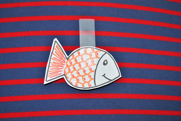 Paper fish cutout taped to the back of a striped shirt, a classic April Fools' prank.
