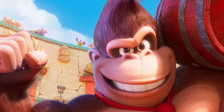 Animated Donkey Kong grins closely at the camera while holding a barrel outdoors.