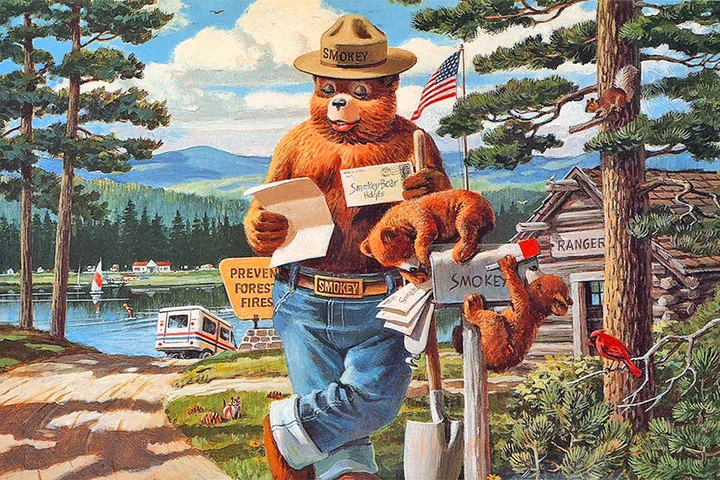 Illustrated Smokey Bear in ranger uniform reading mail outside a forest ranger station.