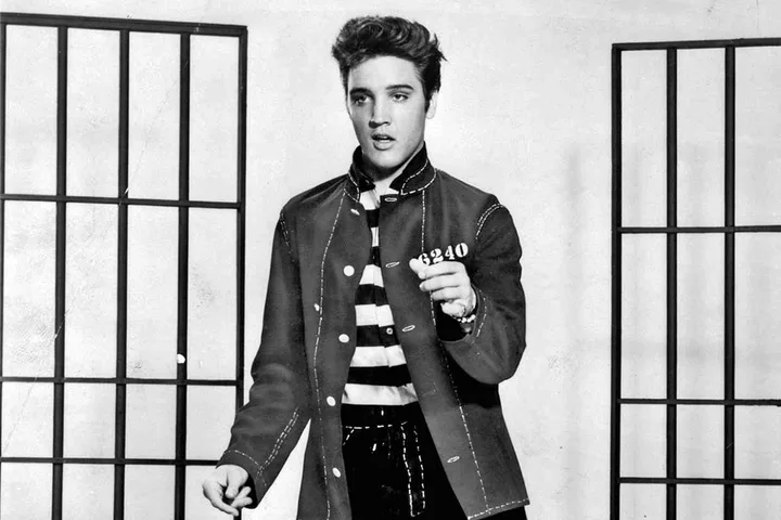 Black and white photo of Elvis Presley in a military-style jacket posing dramatically.