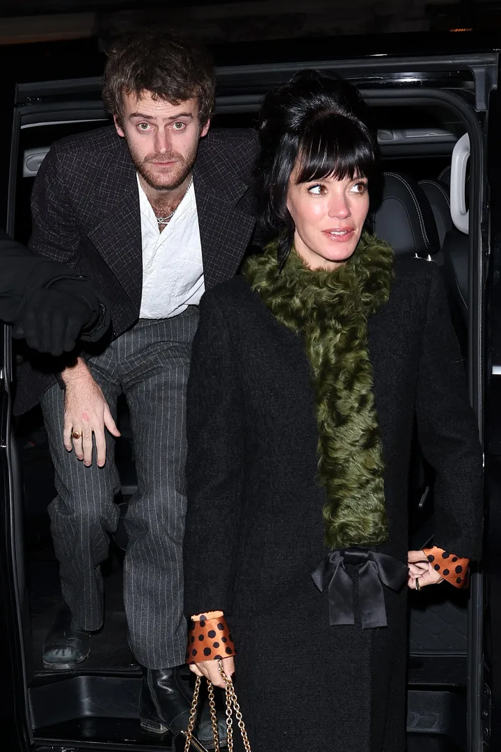 A man and woman stepping out of a vehicle together at night, dressed in stylish outerwear.