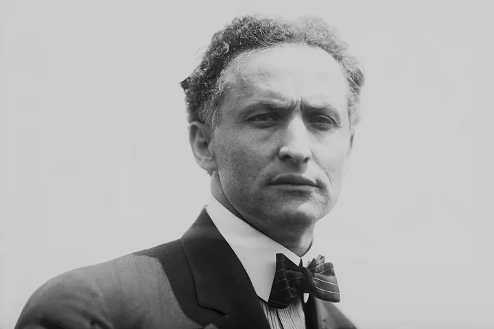 Vintage black-and-white portrait of an intense-looking man in a suit and bow tie.