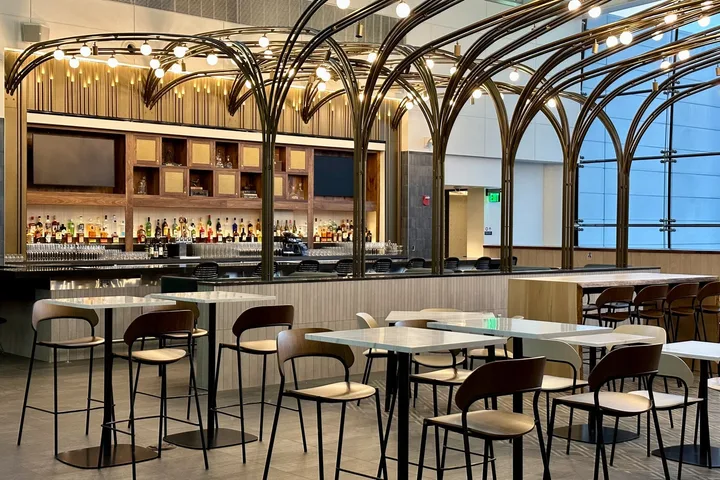 Elegant lounge bar area with arched gold framework, full liquor shelf, and dining tables.