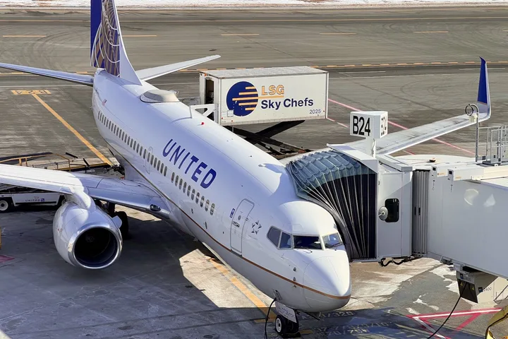 United Airlines Boeing 737 at gate with jetbridge and catering truck attached.