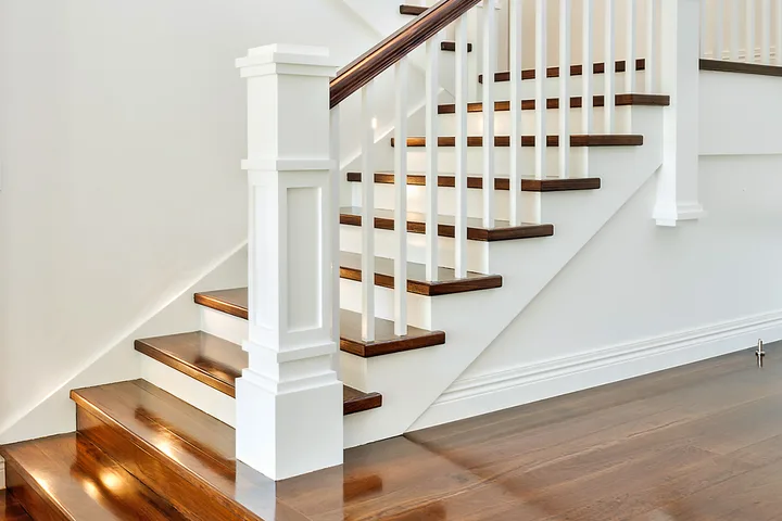 Elegant white and dark wood staircase with decorative newel post in a bright home interior.