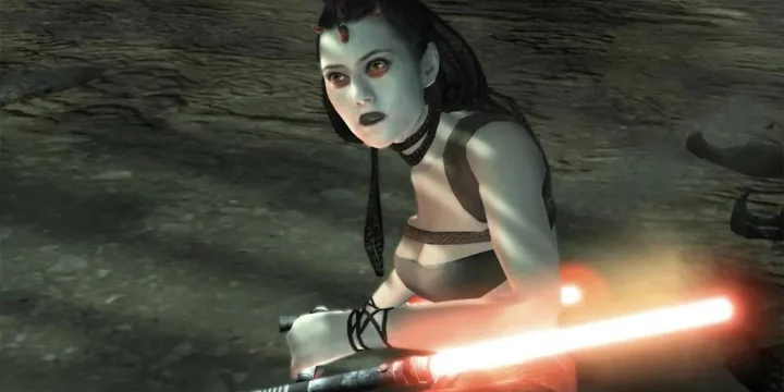 Pale-skinned dark side female character holding a red lightsaber in a cave, appears from a video game.