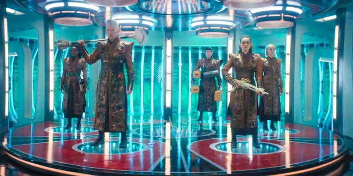 Group of alien warriors in ornate robes standing on a glowing transporter pad.