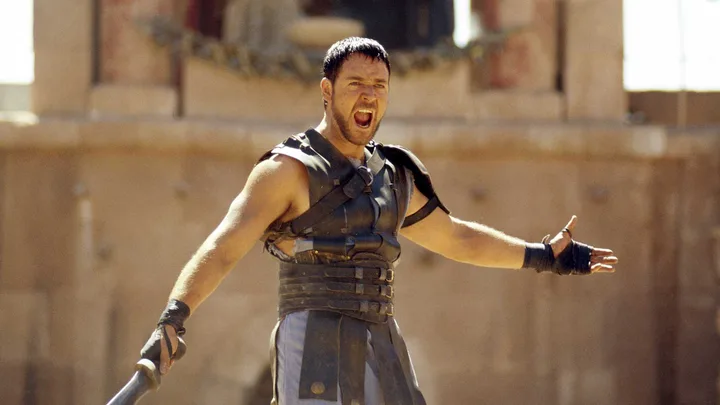 Man in gladiator armor shouting triumphantly in an ancient Roman colosseum setting.