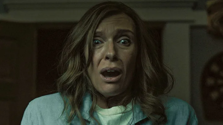 Woman with wide terrified eyes and open mouth in dark horror movie scene.